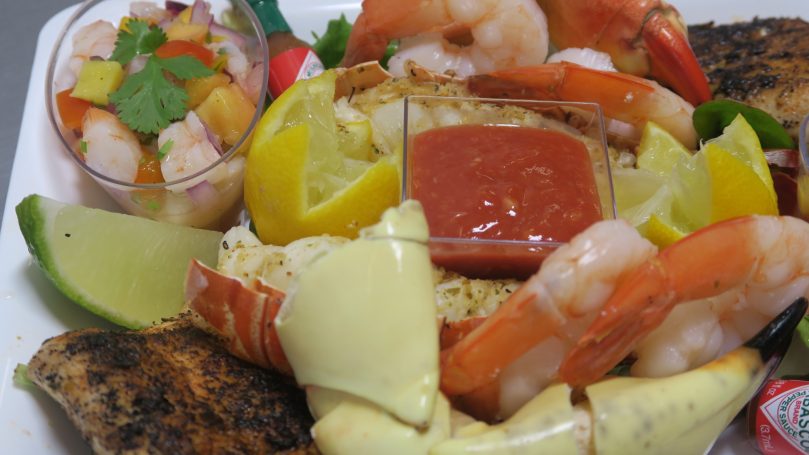 A mixed seafood platter featuring shrimp, fish, lemon, and salsa.