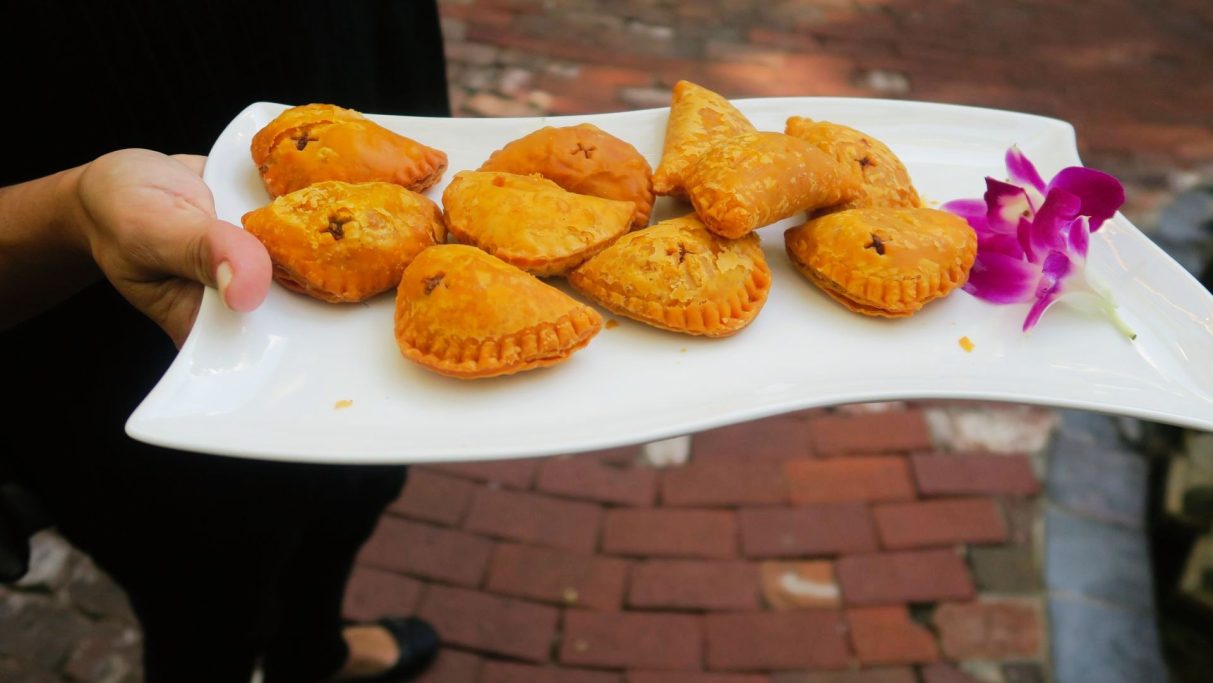 A plate of golden-brown pastries with a purple flower garnish.