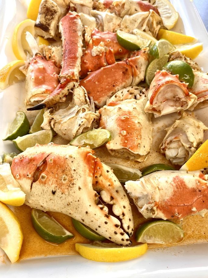 Cooked crab clusters garnished with lemon and lime slices on a white platter.