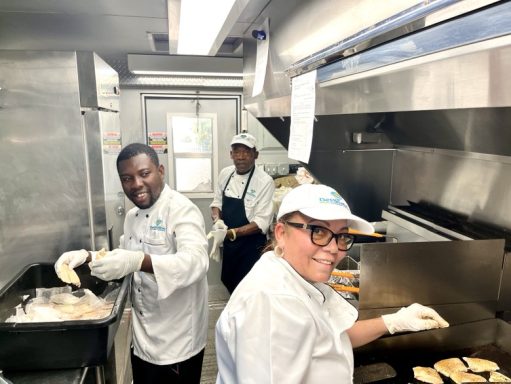 Chefs preparing food in a kitchen, smiling and working together.