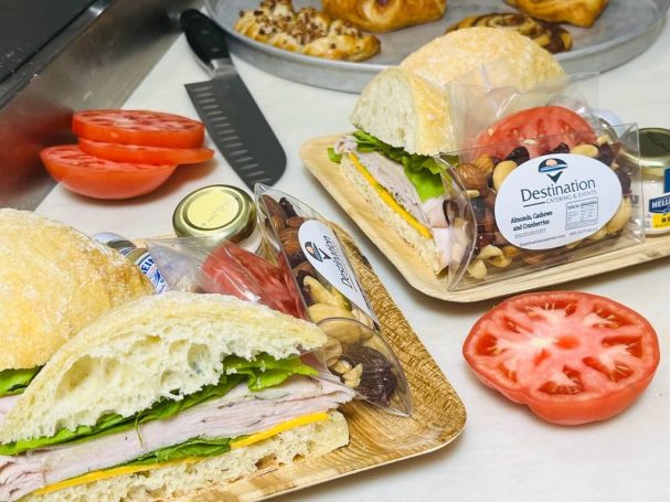 Turkey Sandwich A turkey sandwich with lettuce and tomato, accompanied by a side of nuts and additional tomato slices.