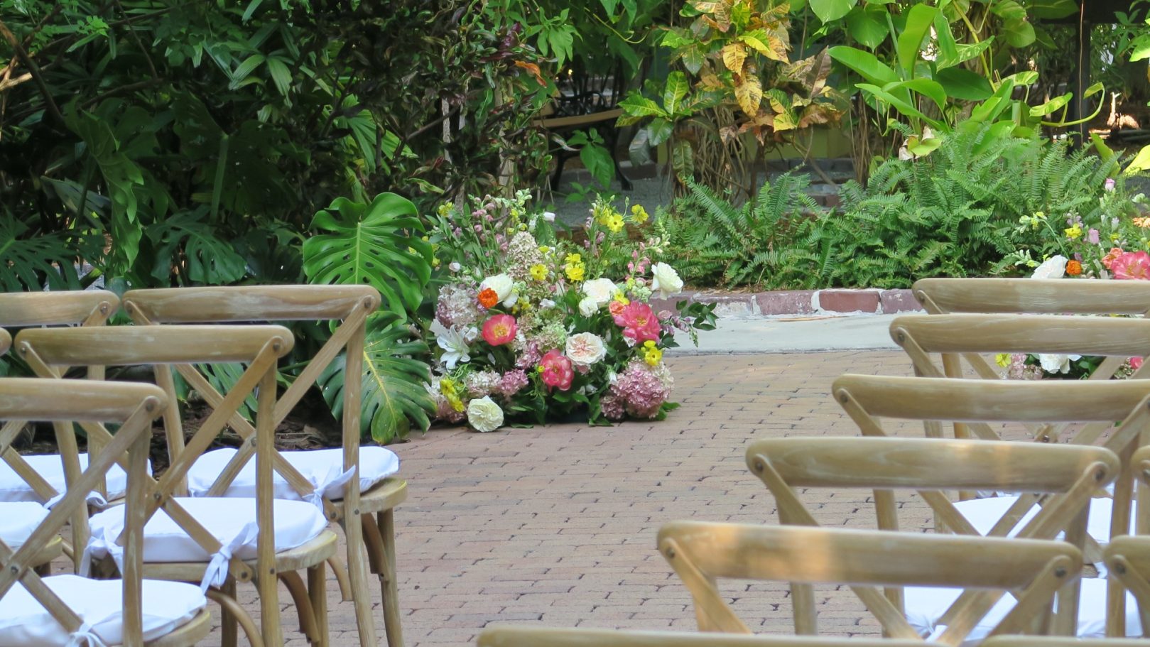 Garden Wedding Ceremony An outdoor wedding setup with chairs and a colorful floral arrangement.
