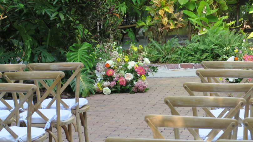 An outdoor wedding setup with chairs and a colorful floral arrangement.