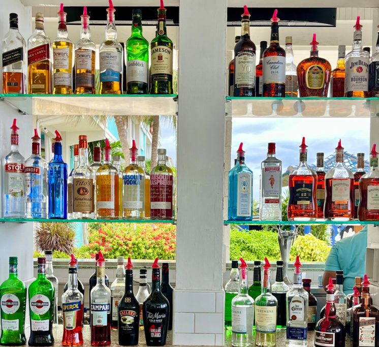 Shelf filled with various liquor bottles in a bar setting.