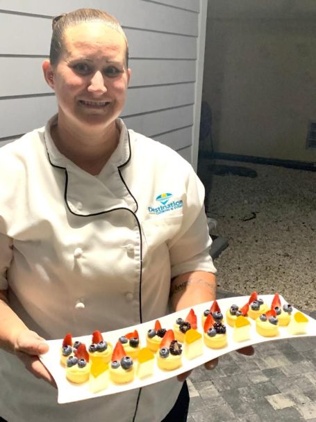 Chef A. with her mini dessert creations. A chef holding a platter of dessert cups topped with fruit and cream.