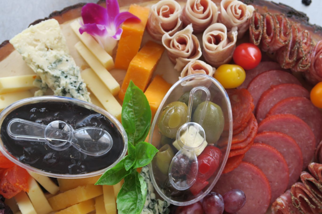 Charcuterie Board Assorted meats, cheeses, olives, grapes, and garnishes arranged on a wooden platter.