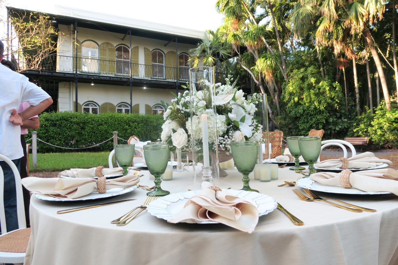 Wedding Table Setting Elegant outdoor dining setup with a floral centerpiece and green glassware.