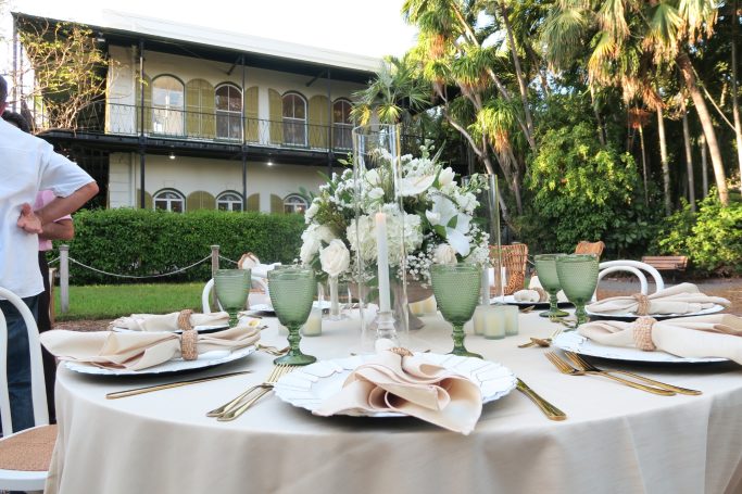 Elegant outdoor dining setup with a floral centerpiece and green glassware.